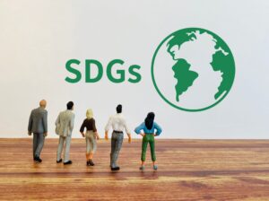 SDGsの文字と緑色の地球を見つめる人々の模型
